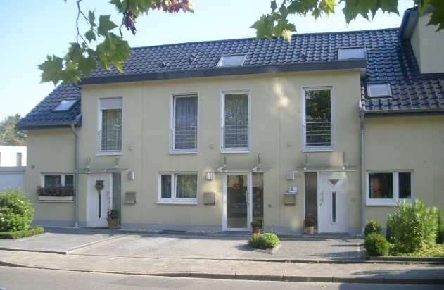 Von Vierbau errichtetes, fertiggestelltes Wohnhaus in Mönchengladbach mit hellem Putz und dunklem Dach an einem sonnigen Tag.